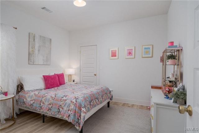 bedroom with visible vents, baseboards, and wood finished floors