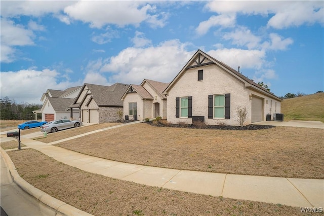 view of front of home featuring driveway, brick siding, an attached garage, cooling unit, and a front yard