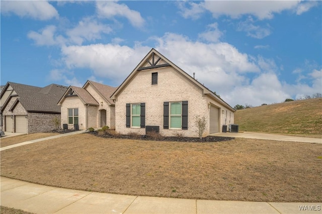 view of front of home with brick siding, central AC unit, a front yard, a garage, and driveway