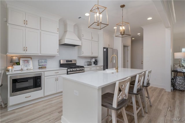 kitchen with appliances with stainless steel finishes, light wood-type flooring, light countertops, and custom range hood