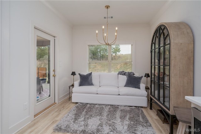 living area featuring a healthy amount of sunlight, light wood-style floors, and a notable chandelier