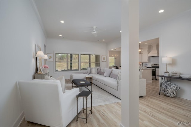 living area with light wood-type flooring, ceiling fan with notable chandelier, crown molding, and recessed lighting