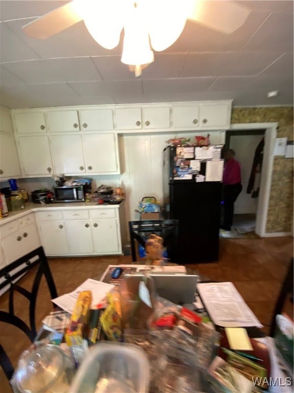 kitchen featuring white cabinets, ceiling fan, and black refrigerator