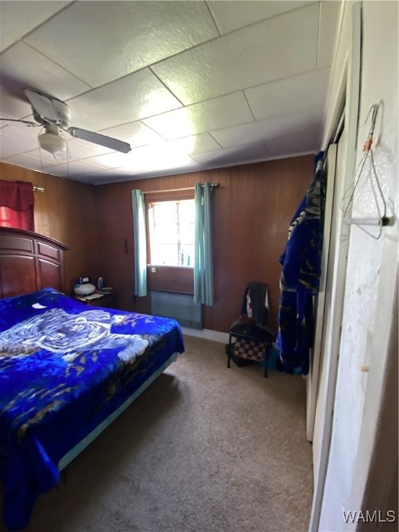 bedroom with carpet flooring, ceiling fan, and wood walls