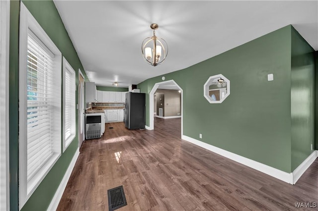44 Maddox Rd, Nauvoo, AL 35578 - unfurnished living room with an inviting chandelier, arched walkways, visible vents, dark wood-style flooring, and baseboards