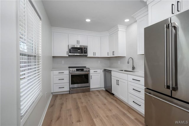 kitchen featuring light countertops, light wood-style flooring, appliances with stainless steel finishes, white cabinetry, and a sink