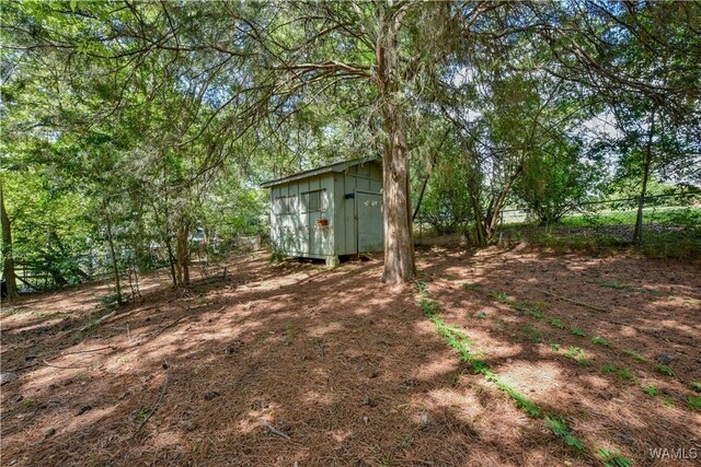 view of yard featuring an outbuilding, a shed, and fence