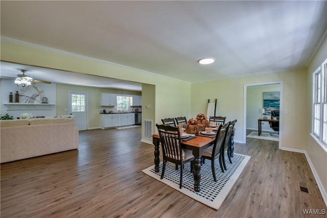 dining area featuring crown molding, wood finished floors, visible vents, and baseboards