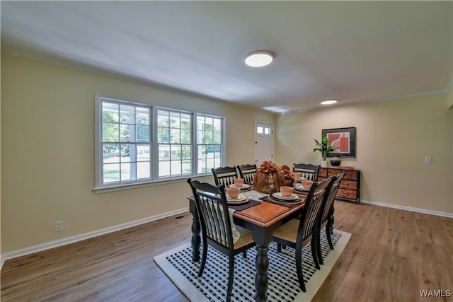 dining room featuring crown molding, baseboards, and wood finished floors