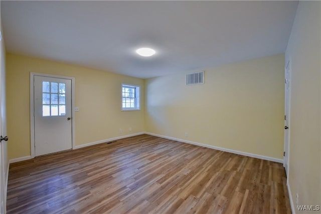 unfurnished room with baseboards, visible vents, and wood finished floors