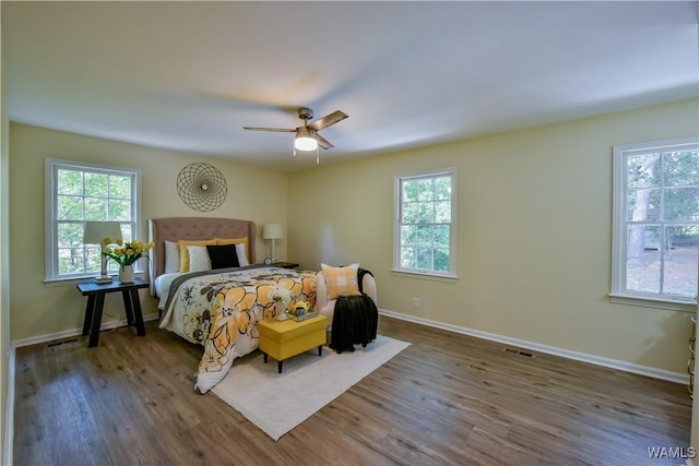 bedroom featuring multiple windows, wood finished floors, visible vents, and baseboards