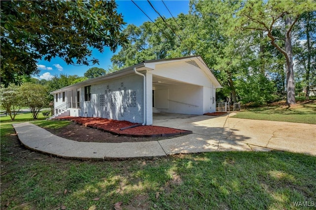 view of side of property featuring an attached carport, concrete driveway, brick siding, and a lawn