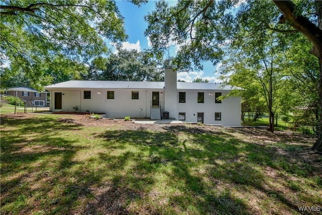 back of property with a chimney, metal roof, and a lawn