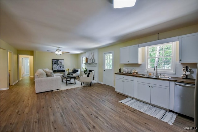 kitchen with a sink, a large fireplace, dishwasher, and wood finished floors