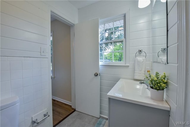 half bathroom with toilet, wood finished floors, and vanity