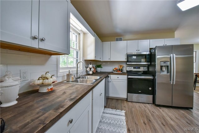 kitchen featuring visible vents, appliances with stainless steel finishes, white cabinetry, a sink, and wood counters