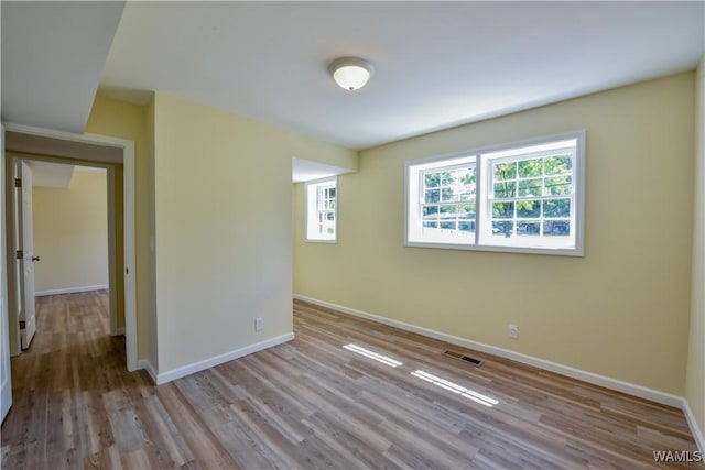 empty room featuring wood finished floors, visible vents, and baseboards