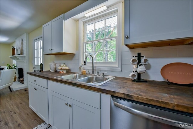 kitchen featuring a sink, butcher block countertops, a fireplace, and dishwasher