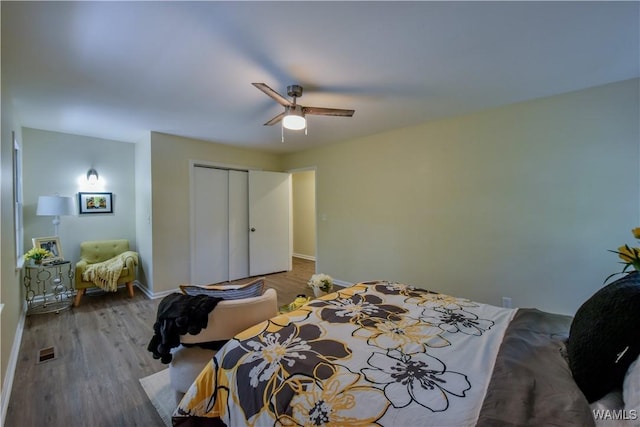 bedroom with baseboards, visible vents, ceiling fan, wood finished floors, and a closet