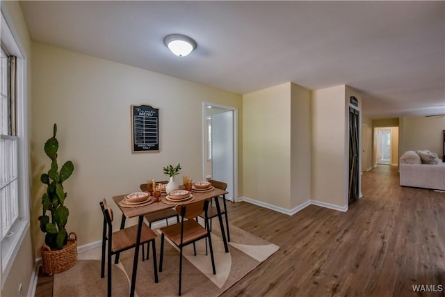 dining area with baseboards and wood finished floors