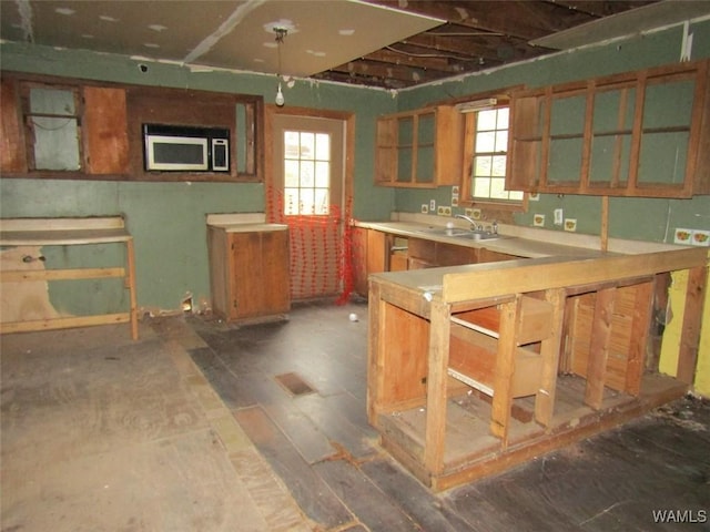 kitchen featuring light countertops, stainless steel microwave, visible vents, glass insert cabinets, and a sink