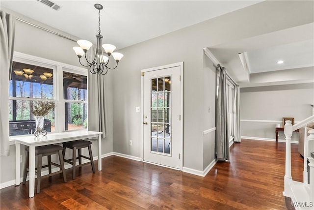 dining room featuring a tray ceiling, dark wood-type flooring, and an inviting chandelier