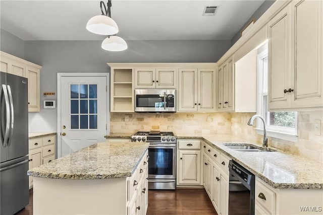 kitchen with a center island, sink, decorative light fixtures, light stone counters, and stainless steel appliances