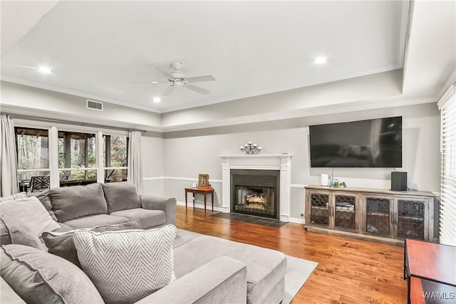 living room featuring hardwood / wood-style floors, ornamental molding, ceiling fan, and a healthy amount of sunlight