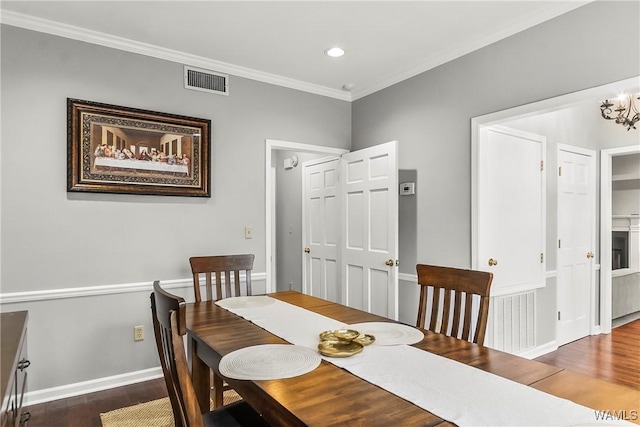 dining room with dark hardwood / wood-style floors, ornamental molding, and an inviting chandelier