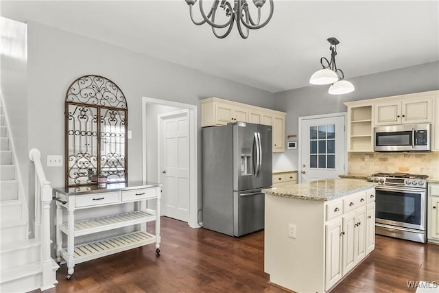 kitchen featuring dark wood-type flooring, stainless steel appliances, light stone counters, pendant lighting, and a kitchen island