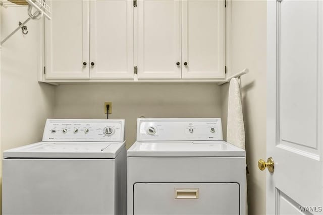 clothes washing area featuring washing machine and dryer and cabinets