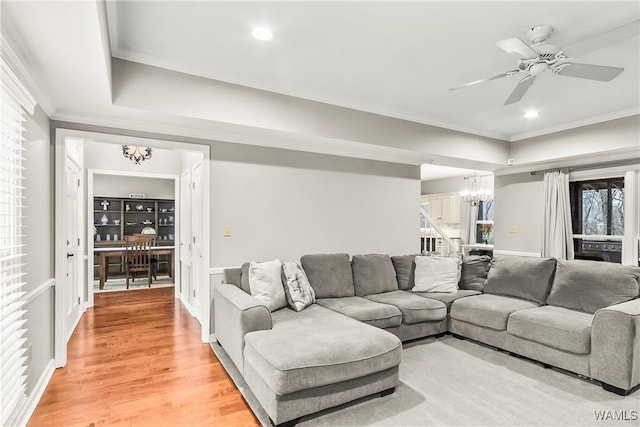 living room with hardwood / wood-style floors, ceiling fan with notable chandelier, and crown molding