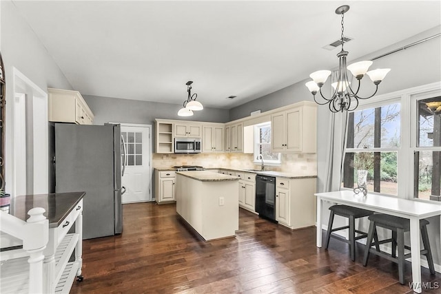 kitchen featuring appliances with stainless steel finishes, tasteful backsplash, a kitchen island, and pendant lighting