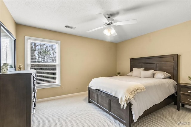 carpeted bedroom featuring ceiling fan and a textured ceiling