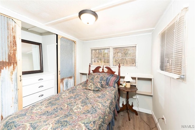 bedroom with wood finished floors, baseboards, and a closet
