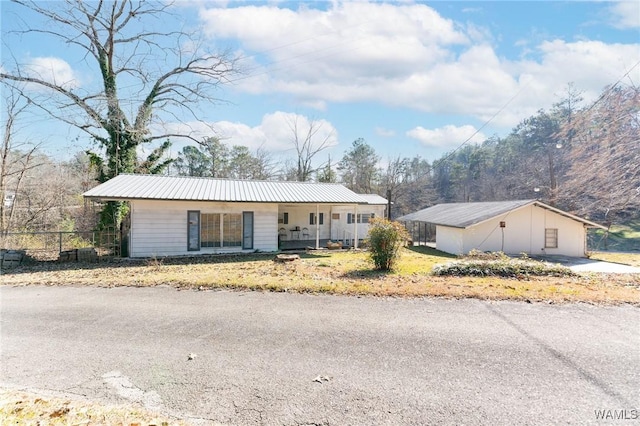 single story home featuring fence, covered porch, and metal roof