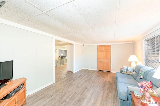 living room featuring light wood-type flooring, baseboards, and a drop ceiling