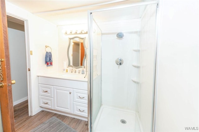 full bathroom with a stall shower, wood finished floors, and vanity