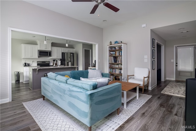 living room with dark hardwood / wood-style floors, ceiling fan, and sink