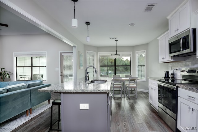 kitchen with stainless steel appliances, a center island with sink, a healthy amount of sunlight, and sink