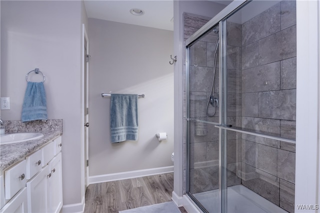 bathroom with hardwood / wood-style floors, vanity, toilet, and walk in shower