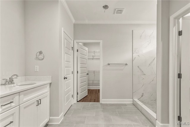 bathroom with tile patterned floors, vanity, tiled shower, and crown molding