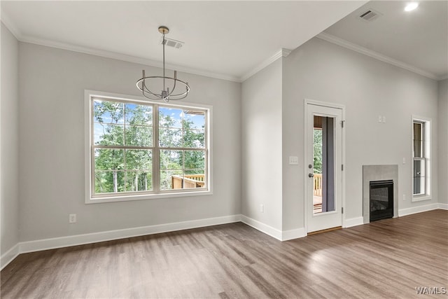 unfurnished living room with a tile fireplace, a wealth of natural light, an inviting chandelier, and hardwood / wood-style flooring