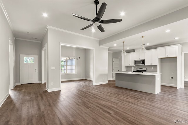 kitchen with appliances with stainless steel finishes, a kitchen island with sink, crown molding, dark hardwood / wood-style floors, and white cabinetry