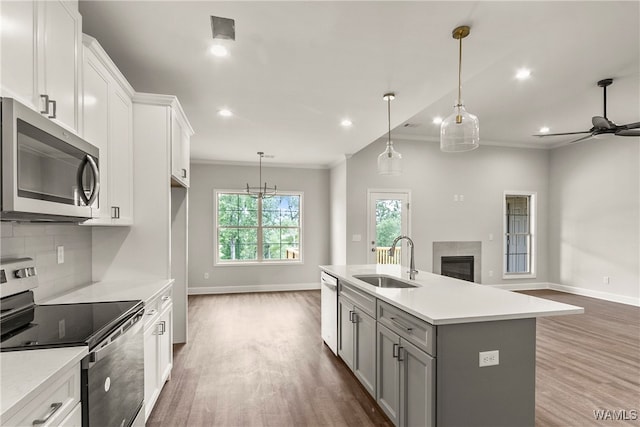 kitchen with appliances with stainless steel finishes, dark wood-type flooring, sink, white cabinetry, and an island with sink