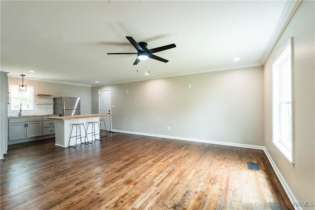 unfurnished living room featuring dark wood-style flooring, ceiling fan, and baseboards