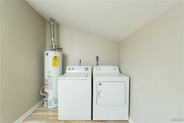 clothes washing area with gas water heater, light wood finished floors, washer and clothes dryer, laundry area, and baseboards