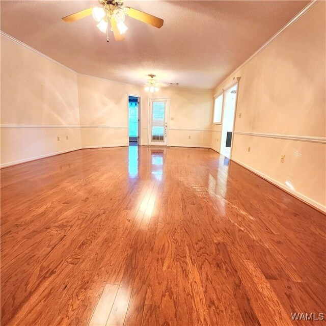 empty room with ceiling fan, crown molding, wood-type flooring, and a textured ceiling