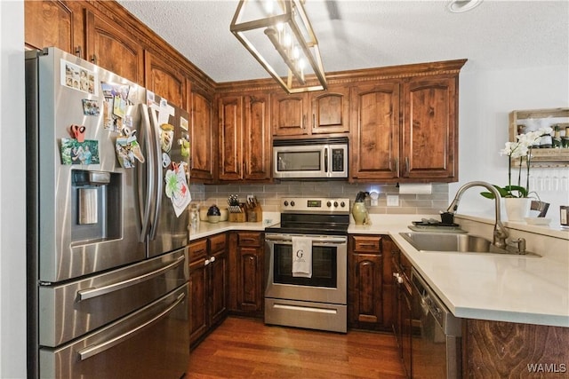 kitchen with light countertops, a textured ceiling, a sink, appliances with stainless steel finishes, and backsplash