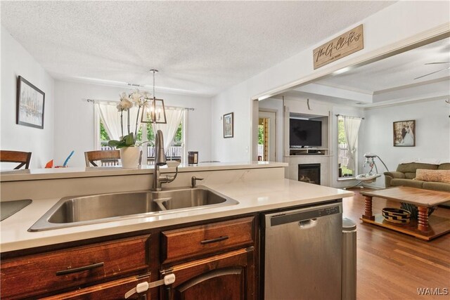 kitchen featuring a sink, light countertops, stainless steel dishwasher, and open floor plan